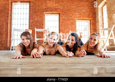 Portrait de groupe de jeunes excités sportive de belles filles avec des tapis d'entraînement debout à côté de mur blanc rire et parler ensemble. Banque D'Images