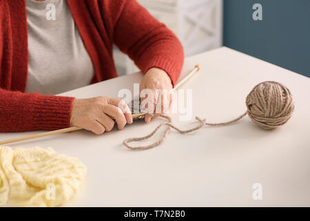 Senior woman knitting écharpe à table Banque D'Images