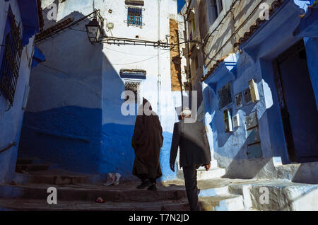 Chefchaouen, Maroc : deux hommes à pied dans les ruelles de la médina bleu à la chaux vieille ville. Banque D'Images