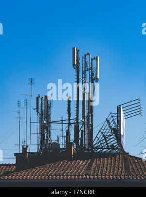 Plan large de différentes antennes antenne radio pour la télévision et le mobile de transmission sur roof tile building against blue sky Banque D'Images