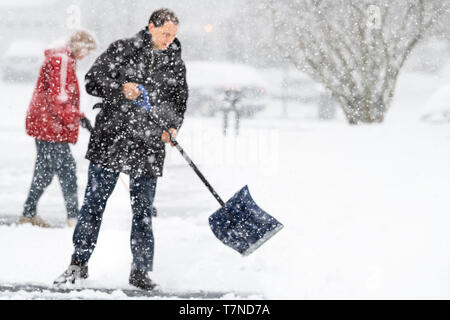 Jeune homme et femme manteau d'hiver en face de l'entrée de pelletage de nettoyage dans la neige Tempête de neige lourde avec pelle et abstrait floue floue sno Banque D'Images