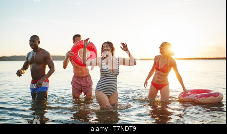 Divers groupes de jeunes amis de rire et de projections d'eau dans un lac sur une après-midi de fin d'été Banque D'Images