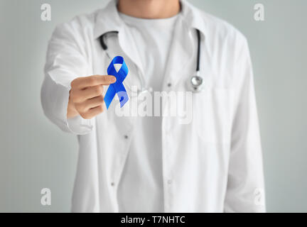 Doctor holding ruban bleu sur fond clair. Concept du cancer de la prostate Banque D'Images