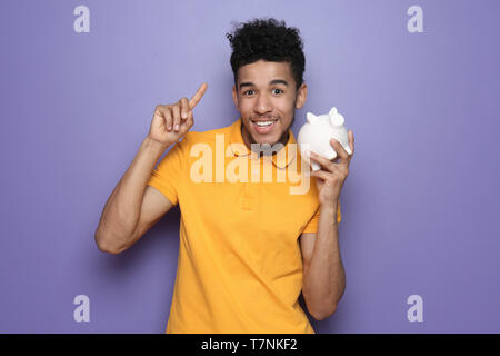 L'homme afro-américain avec tirelire sur un fond de couleur Banque D'Images