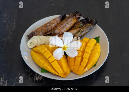 De style thaïlandais, dessert, mangue banane jaune avec le riz gluant en feuilles de palmier. Mangue jaune et le riz collant est populaire traditionnelle de la Thaïlande. Fermer u Banque D'Images