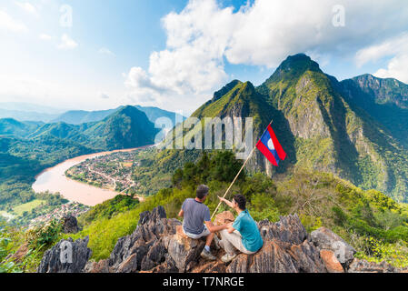 Couple à la conquête de montagne à Nong Khiaw vue panoramique sur la vallée de la rivière Nam Ou au Laos drapeau national scenic mountain landscape célèbre billet destin Banque D'Images