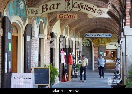Vicoforte, Italie - 17 août 2016 : arcade en briques rouges autour de Sanctuaire de Vicoforte église avec des gens et des magasins dans une journée d'été dans le Piémont, Italie Banque D'Images