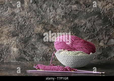 Panier avec fil à tricoter et des aiguilles sur la table contre dark background Banque D'Images