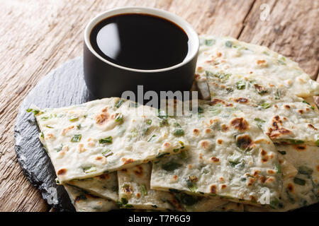 Chewy, feuilletée, et salé scallion pancakes à la sauce gros plan sur une planche sur la table horizontale. Banque D'Images