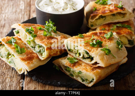 Afghani Bolani avec purée de pommes de terre et les oignons verts servi avec du yogourt nature libre sur la table horizontale. Banque D'Images