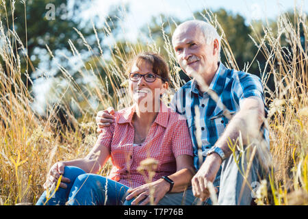 Senior couple sitting dans l'herbe s'amuser Banque D'Images