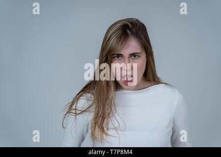 Agacé irrité jeune adolescent à la fille en colère et fou. Se sentant frustrés faisant des gestes furieux. Close up studio shot isolé sur dos neutre Banque D'Images