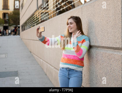 Heureux jolie fille adolescente à l'aide de smart mobile phone heureux soufflant un baiser et forme à des disciples des amis ou de la famille de l'enregistrement vidéo et de chatter. Vide Banque D'Images