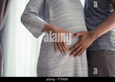 Le couple part faire heart shape on pregnant belly Banque D'Images