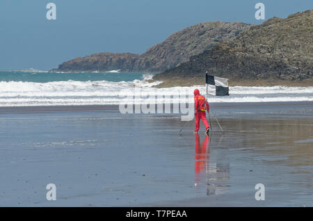 Sauvetage sur plage, style gallois, comme sauveteur met les drapeaux sur une journée froide à Whitesands Bay sur la côte du Pembrokeshire, Pays de Galles de l'ouest Banque D'Images