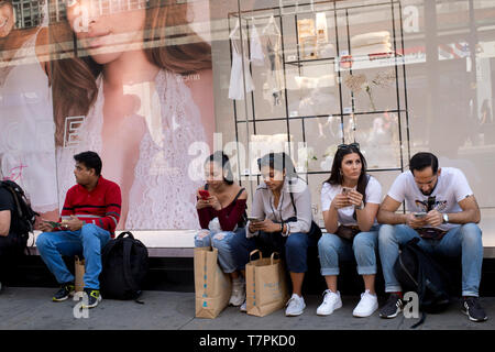 Avril 2019 à Londres. Le Shopping, Oxford Street. Vérifier l'extérieur de leur téléphone Shoppers Primark Banque D'Images