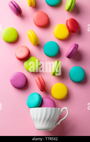 Macarons dessert avec une tasse blanche sur fond pastel rose. Mise à plat de sa composition. Vue d'en haut. Banque D'Images