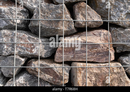 Un gros plan d'un tas de rochers de granit dans une cage métallique utilisé pour la prévention des inondations. Banque D'Images