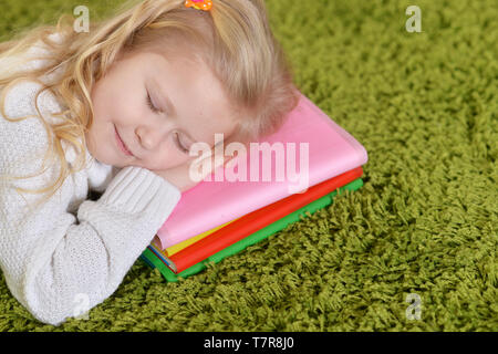 Portrait of cute little girl sleeping on pile of books Banque D'Images