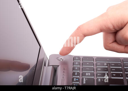 Vue rapprochée de la main avec l'index, en poussant le bouton de démarrage d'argent ordinateur portable avec clavier et écran noir. L'ordinateur tourne sous ou hors tension. Je Banque D'Images