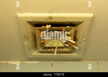 Les cigarettes usagées sont bloquées dans la ventilation des toilettes publiques de l'aéroport comme comportement brut et tabagisme illégal à l'aéroport Banque D'Images