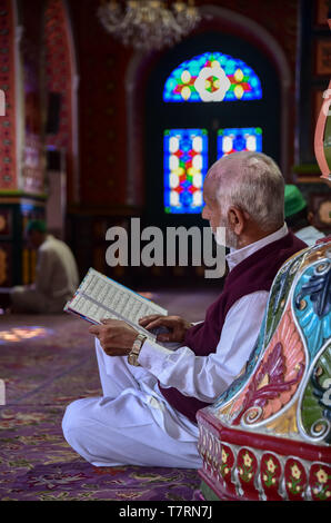 Un homme âgé vu lire un Coran à l'intérieur d'un lieu de culte sur le deuxième jour du mois sacré du Ramadan à Srinagar. Le mois le plus saint de l'Islam Le Ramadan est une période de prière intense, l'aube au coucher du jeûne et de fêtes nocturnes. Banque D'Images