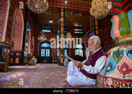 Un homme âgé vu lire un Coran à l'intérieur d'un lieu de culte sur le deuxième jour du mois sacré du Ramadan à Srinagar. Le mois le plus saint de l'Islam Le Ramadan est une période de prière intense, l'aube au coucher du jeûne et de fêtes nocturnes. Banque D'Images