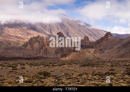 Pierres et rochers de lave autour du volcan couvert par la plantes générique. Haut de Pico del Teide entouré par des nuages blancs. Le parc national du Teide, Tenerif Banque D'Images