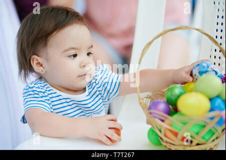 Baby Girl mettre les oeufs de pâques à busket sur le regroupement familial Banque D'Images