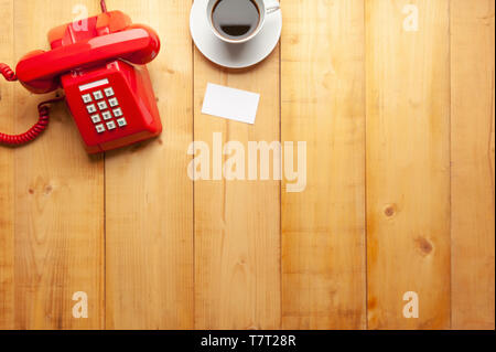 Vue de dessus de l'ancien nom, téléphone rouge et une tasse de café sur plancher en bois , bois texture background, fond en bois naturelle. Banque D'Images