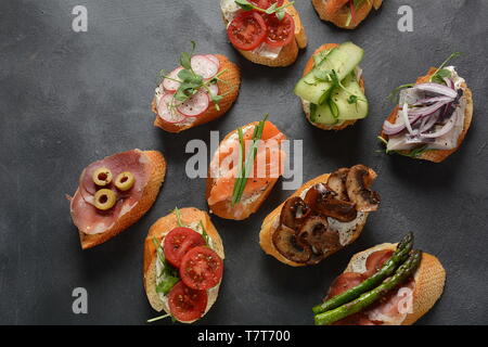 Brushetta ou des tapas espagnoles traditionnelles. Hors-d'antipasti italiens avec des collations. Variété de petits sandwichs au jambon, tomates cerises, du saumon Banque D'Images