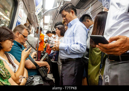 Les personnes à la recherche de leurs smartphones sur la MRT, à Singapour, en Asie du sud-est Banque D'Images