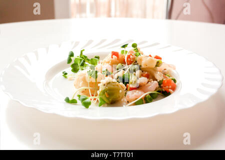 Couscous aux légumes, crevettes et radis sur une plaque blanche Banque D'Images