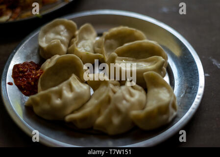 Photo de boulette traditionnelle népalaise à la vapeur momos servi avec Chutney de tomates, sauce schezwan dans Himalaya Banque D'Images