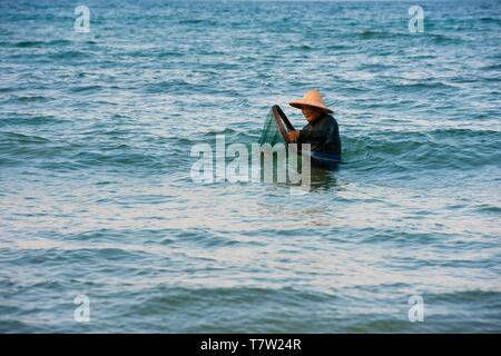 Crabfisher avec chapeau de paille dans l'eau, la plage Cua Dai, près de Hoi An, Vietnam Banque D'Images