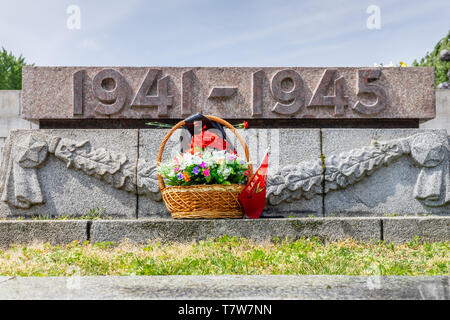 Fleurs devant une tombe de la seconde Guerre mondiale d'un soldat soviétique tombé au Mémorial de guerre soviétique, Berlin Treptow le jour de la libération 8 mai, Allemagne Banque D'Images