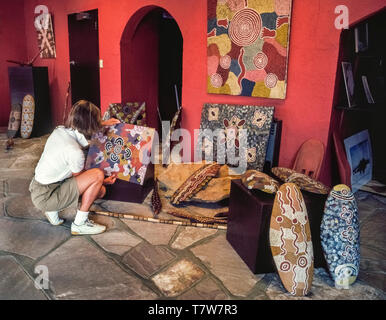 Une femelle d'études touristiques certains de l'art contemporain et de l'artisanat créé avec des dessins traditionnels et des techniques par les Australiens autochtones et offerts à la vente à un galerie d'art autochtone à Alice Springs dans le Territoire du Nord de l'Australie. Banque D'Images