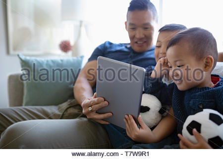 Père et fils using digital tablet sur salon canapé