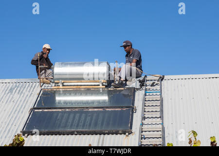 Ouvriers travaillant sur le respect de l'environnement de l'eau chaude solaire sur le toit à l'aide du geyser naturel renouvelable l'énergie du soleil pour le chauffage Banque D'Images