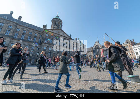 AMSTERDAM, 14 avril 2019 - eau de la soufflante ballon jouer avec les enfants et les enfants sur la Place Dam d'Amsterdam sous le soleil Ciel clair Banque D'Images