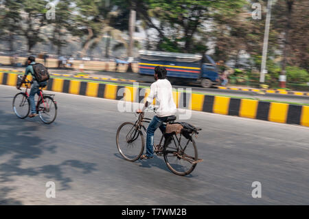 Les jeunes hommes cyling sur une voie publique de la ville de Mumbai, Inde Banque D'Images