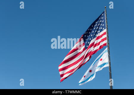 Le drapeau de la ville de Chicago et le drapeau américain dans le vent à Chicago contre ciel bleu clair Banque D'Images