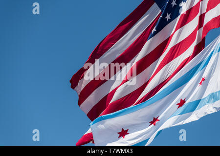 Le drapeau de la ville de Chicago et le drapeau américain dans le vent à Chicago contre ciel bleu clair Banque D'Images