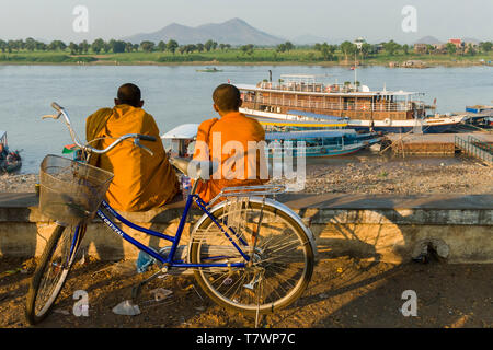 Cambodge, Kampong Chhnang, Tonle Sap, deux moines novices s'assit au bord de la rivière dans la lumière du soir, dans l'arrière-plan le Toum Teav cruise ship Banque D'Images