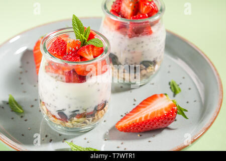 Parfait granola yogourt aux fraises et chia seeds. Délicieux dessert sain pour le petit déjeuner. Lumineux vert menthe spring summer background Banque D'Images