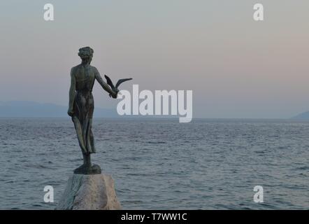 Statue en bronze de fille avec mouette en coucher de soleil, Opatija Banque D'Images