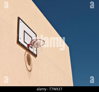 En basket-ball Basket-ball contre mur jaune. La balle et net crée une ombre sur le mur. Banque D'Images