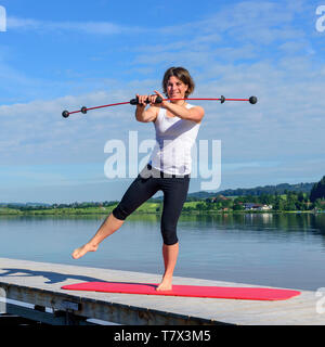 Femme faisant des exercices de Pilates sur un débarcadère dans contreforts des Alpes bavaroises près de Füssen. Banque D'Images