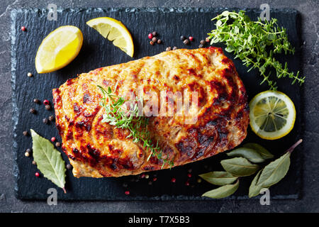 Pain de viande de poulet cuit sur une plaque en ardoise avec les tranches de citron et thym frais sur une table, vue verticale de ci-dessus, mise à plat Banque D'Images