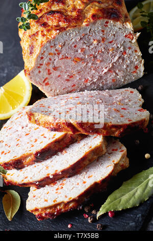 Pain de viande de poulet en tranches sur un plateau en ardoise noire avec les tranches de citron et thym frais sur une table, vue verticale de ci-dessus, close-up Banque D'Images